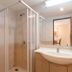 Jomtien Beach Residence in Pattaya bathroom with glass shower, toilet, sink and mirror