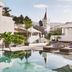 Nobu Hotel Marbella in Marbella with a palm-lined outdoor pool, lounge chairs and church spire view