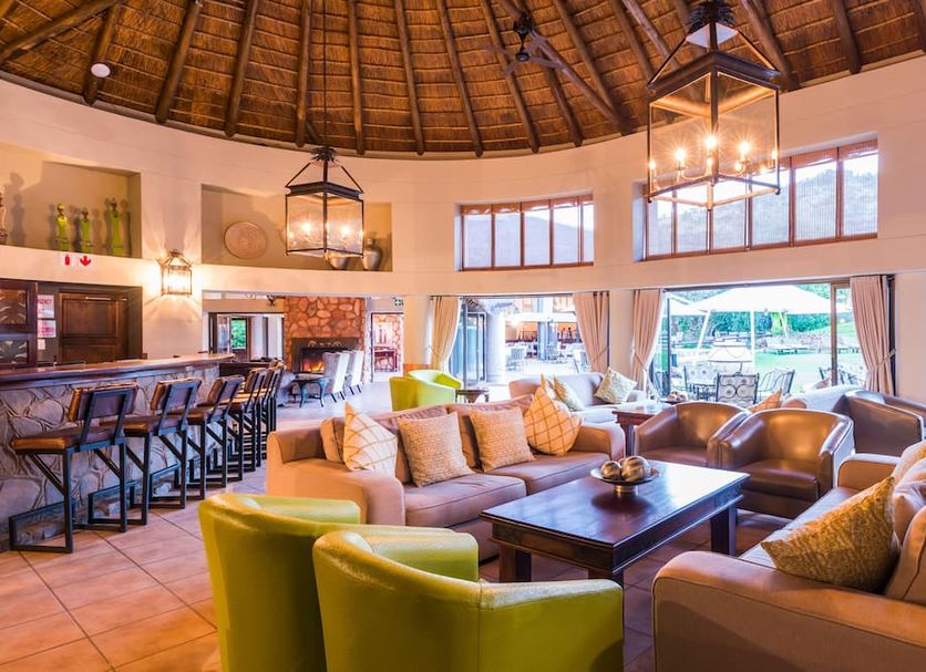 Ivory Tree Game Lodge in Pilanesberg lounge with thatched ceiling, bar, sofas and large windows