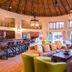 Ivory Tree Game Lodge in Pilanesberg lounge with thatched ceiling, bar, sofas and large windows