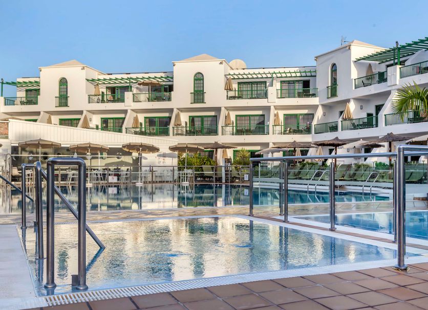Club del Carmen in Tías with a glass-enclosed pool and white apartment-style balconies