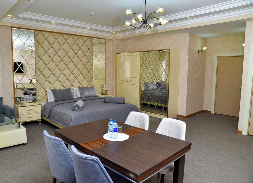 Karat Inn Boutique Hotel Baku guest room with bed, dining table, sofa and mirrored wall panels