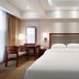 Fulai Garden Hotel in Shenzhen guest room with neatly made bed, desk, lamps, and frosted glass wall