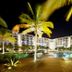 Night view of Playa Blanca Beach Resort in Río Hato with lit pool and palm-lined boardwalk