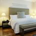 Movich Casa del Alferez in Cali: bright hotel room with king bed, bench, lamps, and hardwood floor