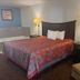 The Magnolia Hotel Searcy in Searcy guest room with king bed, sofa chair, and second bed