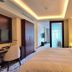 Riviera Rayhaan by Rotana Doha guest room with king bed, desk, and frosted glass door