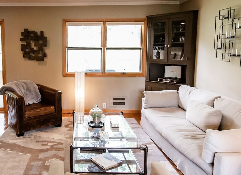 The Broadway Guest House in Granville living room with white sofa, leather chair, glass coffee table, and window view.