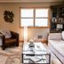 The Broadway Guest House in Granville living room with white sofa, leather chair, glass coffee table, and window view.