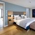The Wellem Düsseldorf guest room with king bed, bench, wood floors and large starry wall art