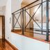 Teichnersuite Rome hallway with wooden floor, ornate doorway, and black railing overlooking stair landing