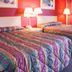 Scottish Inn Downtown Jacksonville in Jacksonville: two beds in a colorful guest room with lamps and curtains