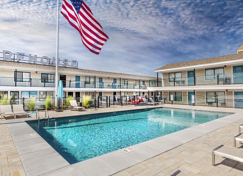 Surf House in Hampton with an outdoor pool and American flag in front of a two-story motel