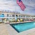 Surf House in Hampton with an outdoor pool and American flag in front of a two-story motel
