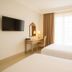 Nims Hotel Seminyak Kuta guest room with two beds, desk, wall-mounted TV and window with curtains