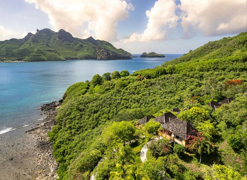 Le Nuku Hiva in Nuku Hiva with hillside bungalows overlooking a tropical bay and mountains.