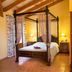 Agroturismo Es Quatre Cantons in Binissalem: four-poster bed, bedside lamps, and mirror-front wardrobe in a warm room.