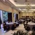 Campago Resort Hotel in Bukittinggi banquet hall with round tables, black chairs, and a chandelier