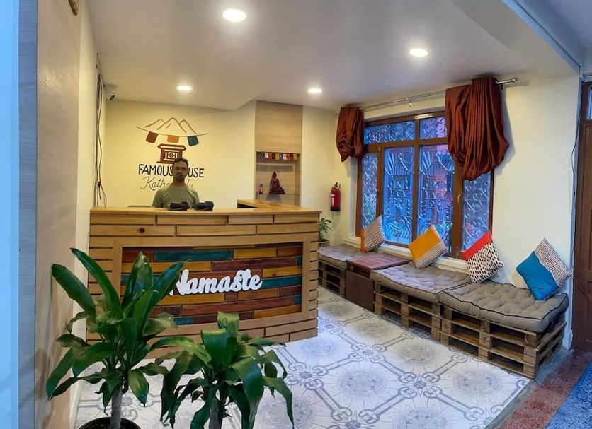 Famous House Kathmandu lobby with wooden reception desk, seating nook, plants and patterned tile floor