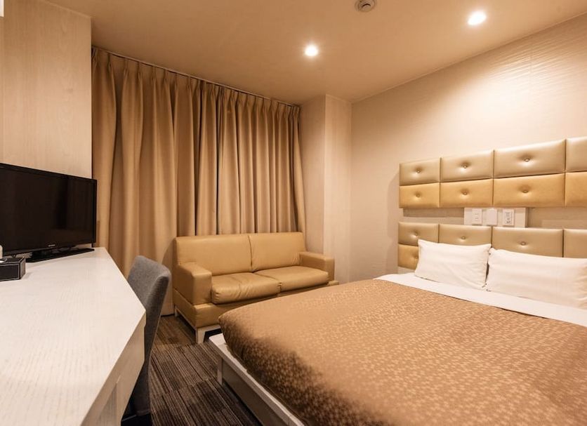 Hotel Relief Sapporo Susukino room with double bed, sofa, desk and TV in Sapporo