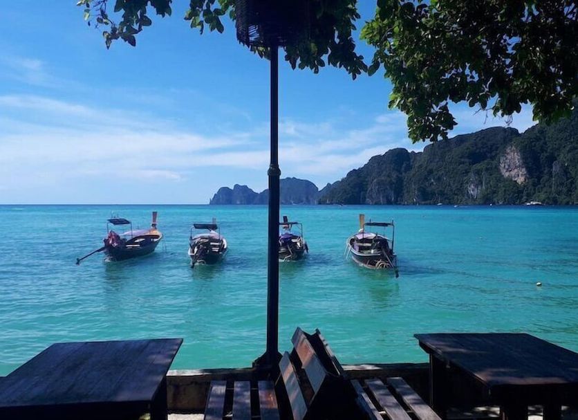 Phi Phi Rimlay Resort in Ko Phi Phi with beachfront tables and longtail boats on turquoise sea