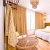 La Palmeraie in La Baule-Escoublac bedroom with wicker chair, yellow curtains and hanging lanterns