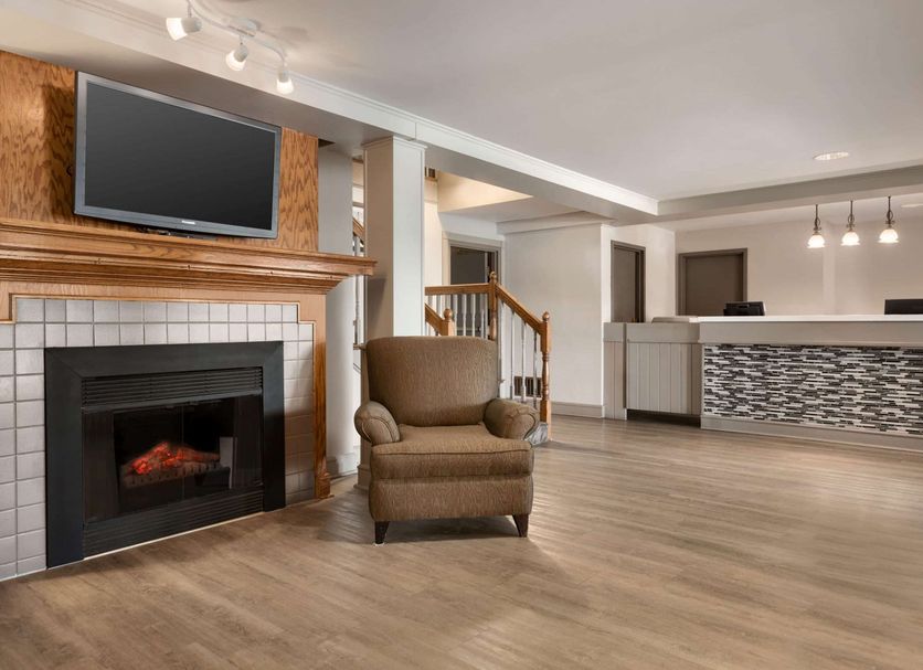 Travelodge Suites by Wyndham New Glasgow lobby with fireplace, armchair and front desk