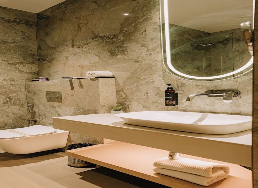 Hotel Punjab Palace Raipur bathroom with marble walls, vessel sink, large mirror and towel shelf