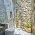 M Village Phu Quoc bathroom with stone walls, walk-in shower, and toilet in Phu Quoc