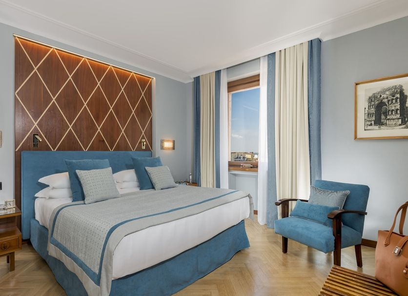 Bettoja Hotel Mediterraneo Rome guest room with king bed, blue armchair, and balcony view