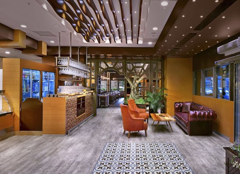 The Merlot Hotel Eskisehir lobby lounge with bar, orange chairs, and leather sofa in Eskişehir
