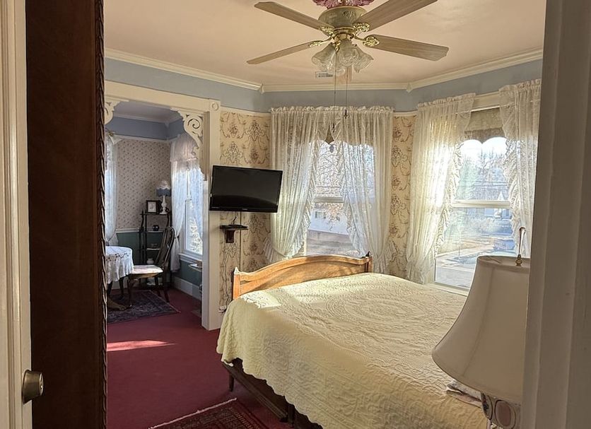 Roseberry House Bed & Breakfast in Susanville bedroom with bed, TV, bay window, and lace curtains