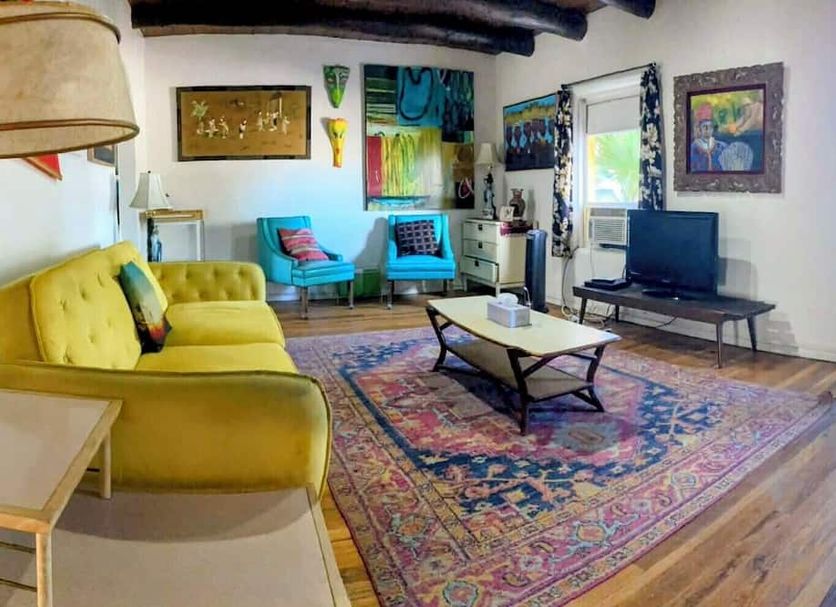 Pelican Spa in Truth or Consequences lounge with yellow sofa, TV, rug, and colorful art