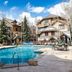 The Osprey at Beaver Creek, A RockResort pool courtyard with mountain lodge buildings and pine trees