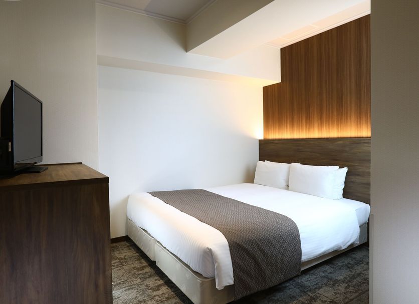 Hotel Hokke Club Kyoto guest room with double bed, wood-paneled headboard, and TV in Kyoto