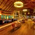 Hurawalhi Island Resort, Komandoo: warm wooden restaurant interior with tables, chairs and ocean-view windows