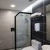 De House Hotel Sibu bathroom with glass shower, toilet, sink, and towel shelf