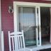 Windjammer BY The Sea in Hampton, sliding glass patio doors and white chairs outside a room