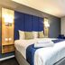 Days Inn by Wyndham London Stansted Airport room with king bed, blue headboard, and window in Bishop's Stortford