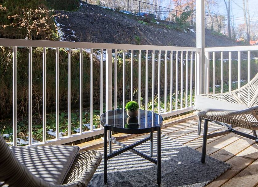 Micro Boutique Living Fredericton patio with wicker chairs, round table, and white railing overlooking greenery