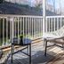 Micro Boutique Living Fredericton patio with wicker chairs, round table, and white railing overlooking greenery