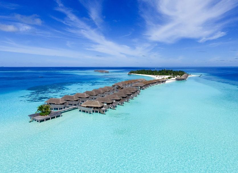 Constance Moofushi overwater villas on Moofushi Island above a turquoise lagoon and blue ocean