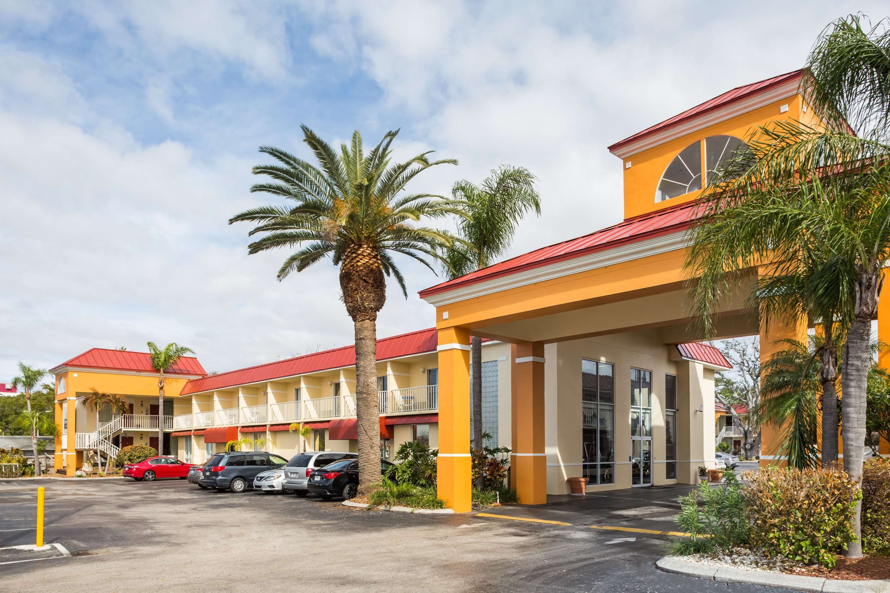 Days Inn & Suites by Wyndham Port Richey exterior with palm trees and covered entrance