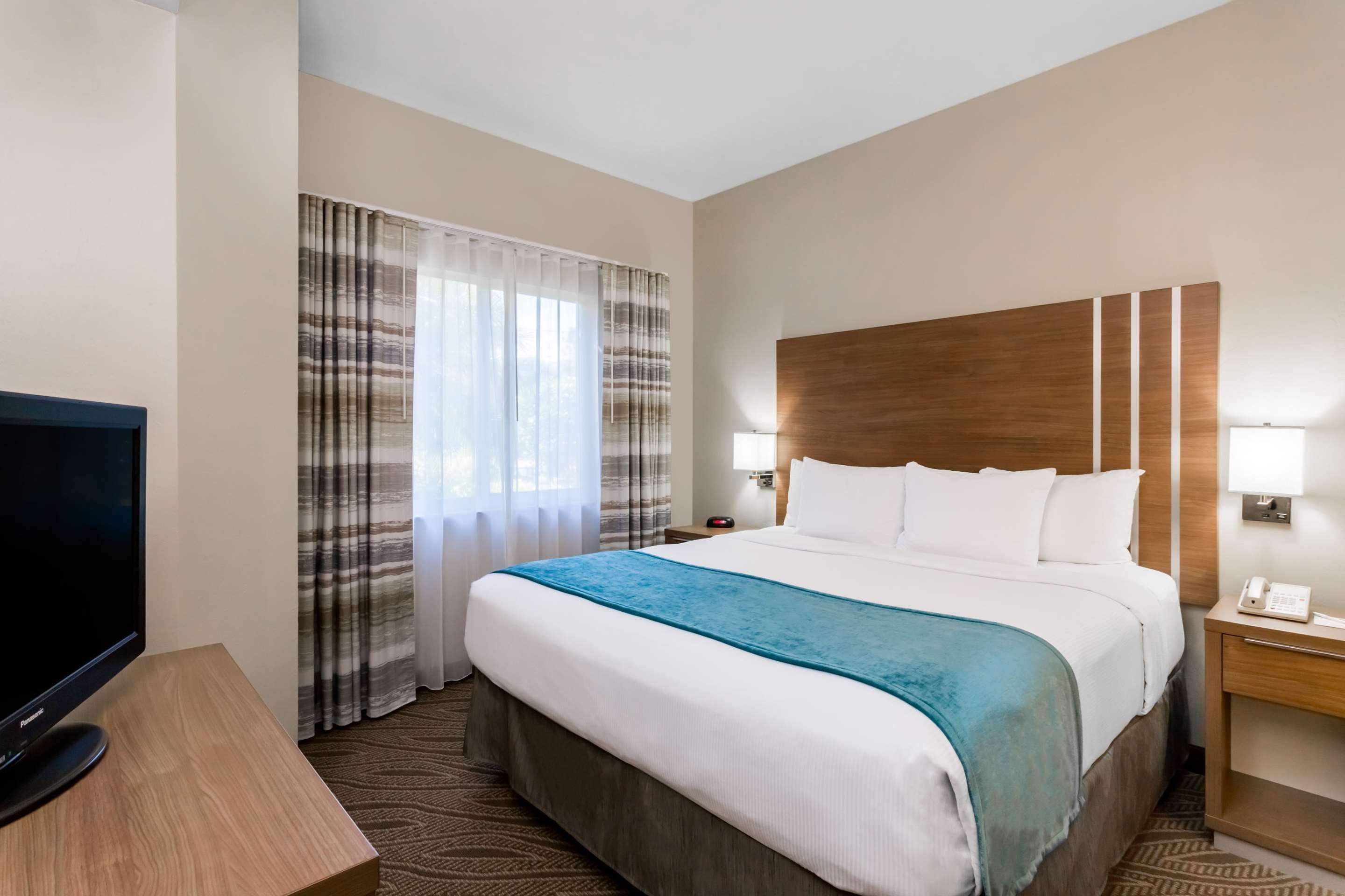 Hawthorn Extended Stay by Wyndham Naples guest room with king bed, window, and bedside lamps