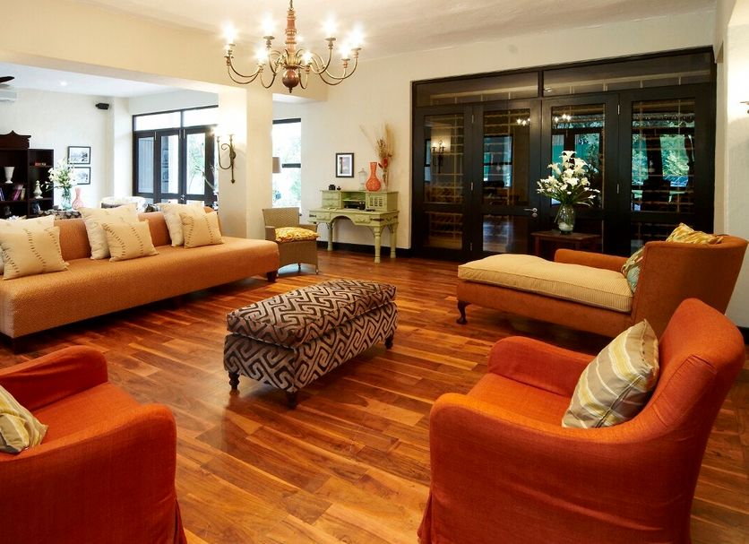 Sandton Lodge Rivonia in Johannesburg lounge with orange armchairs, sofa, chandelier and wood floors