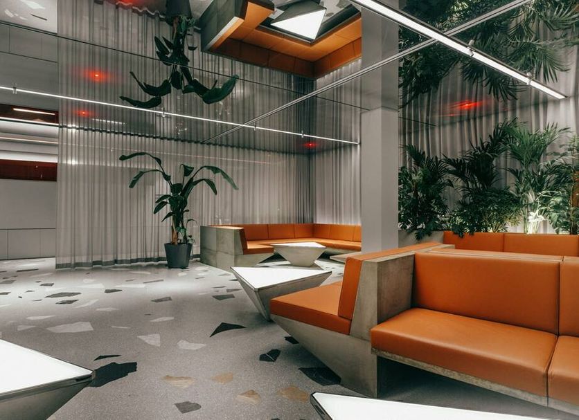 Hotel Josef Prague lobby with orange seating, indoor plants and modern skylight design