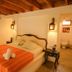 La Casa de Sebas in Máncora: a rustic bedroom with orange bedspread and hanging lanterns