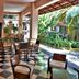 Hôtel du Roi Christophe in Cap Haitien, covered veranda with chairs and tiled floor beside lush garden