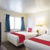 Budgetlodge Oklahoma City room with two beds, blue curtains, window light, and wall lamps
