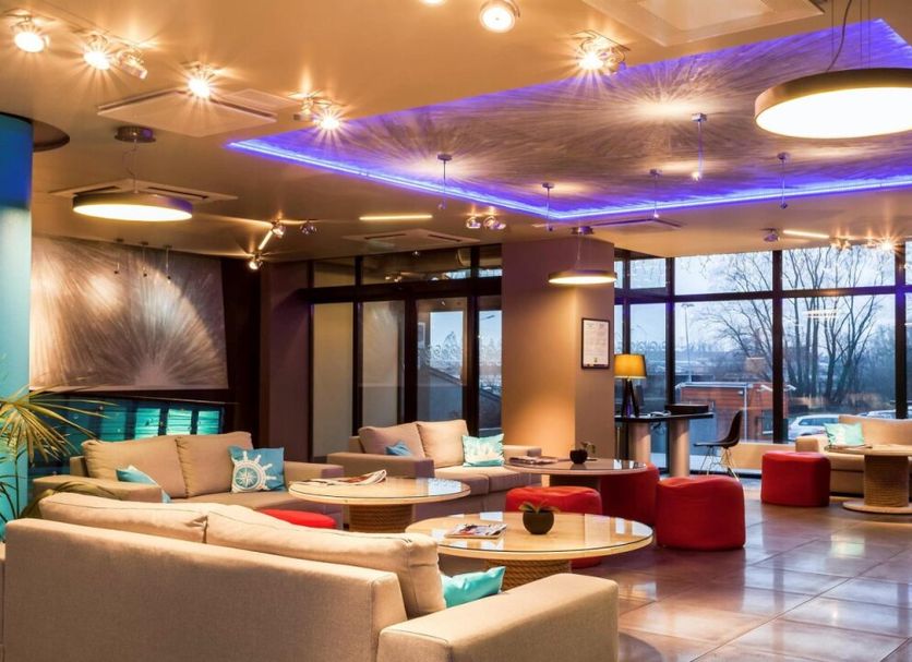 Ibis Styles Riga lounge with colorful seating, circular tables, and large windows in Riga
